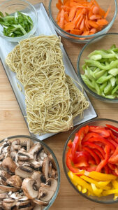 Chow Mein noodles and cut veggies in prep bowls ready for cooking