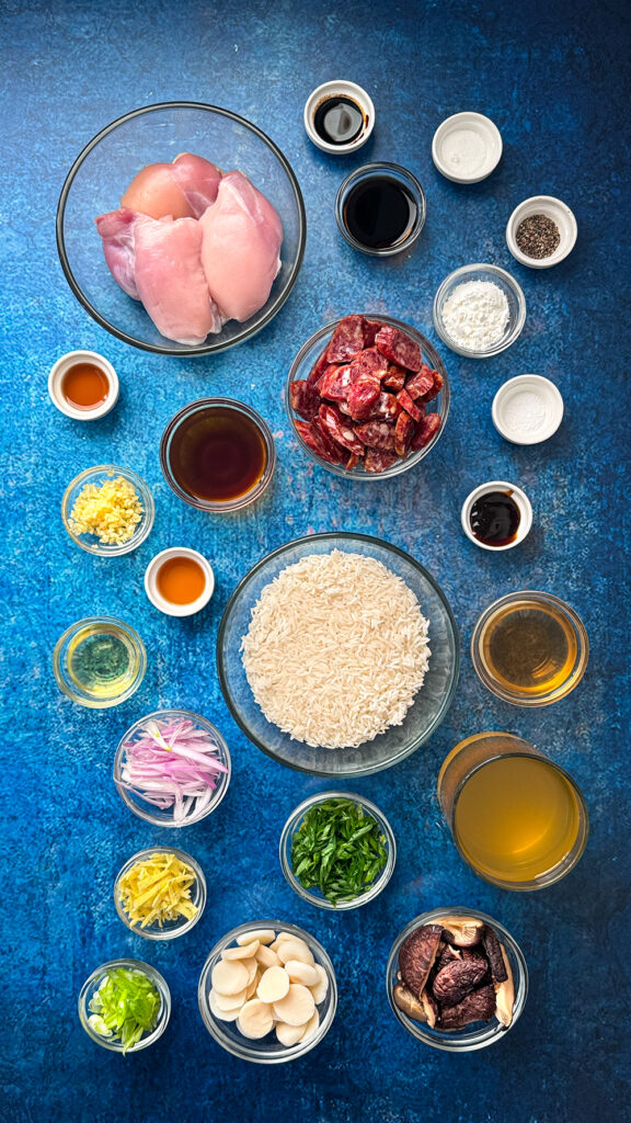Ingredients for Claypot Chicken set out on a blue background in glass bowls.