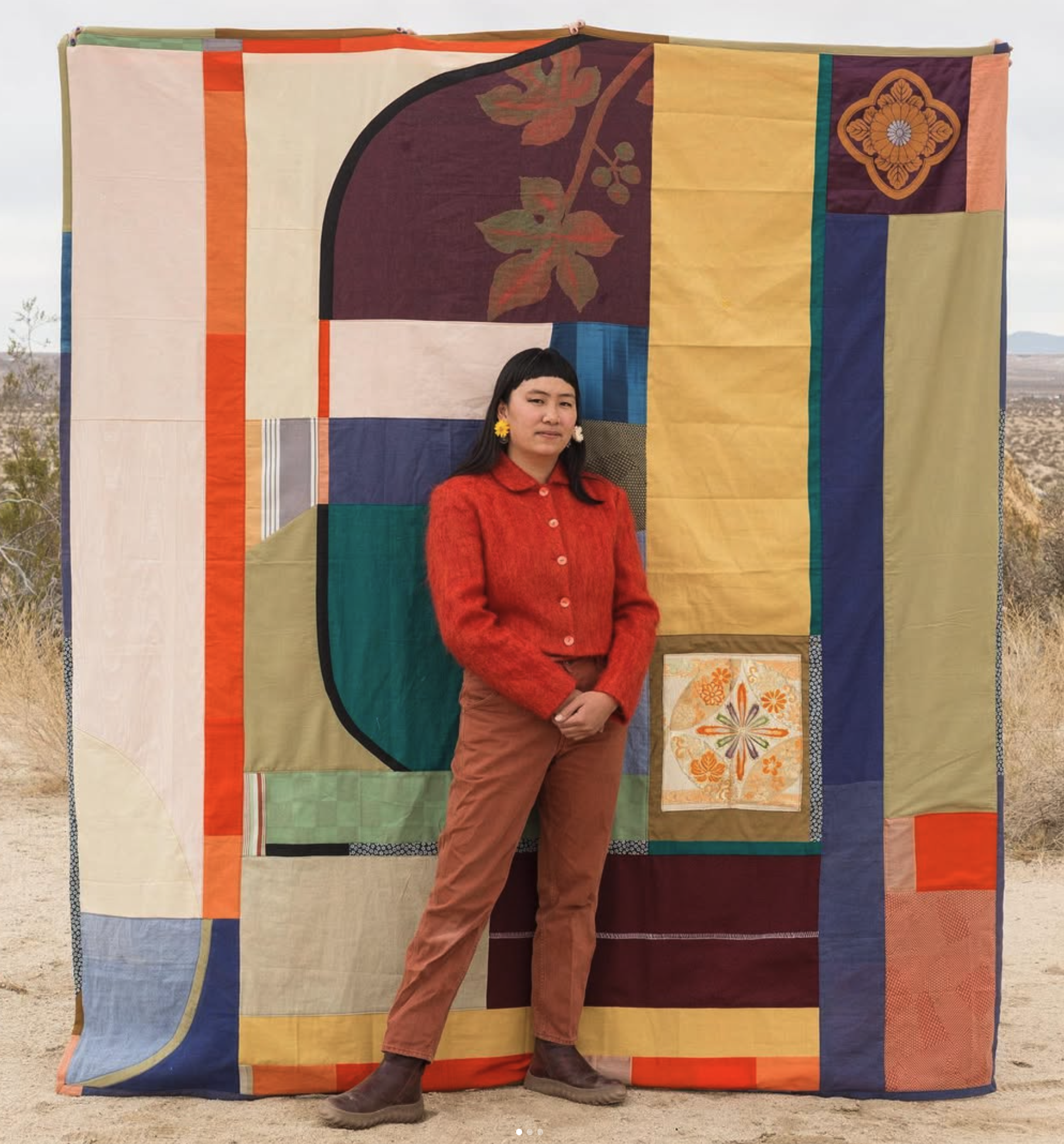 Elena standing in front of a custom bed coverlet stitched out of vintage kimono and obi fabric.